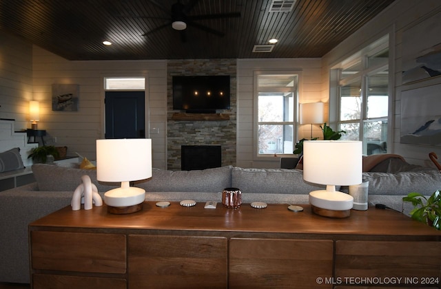 living room featuring wood walls, a fireplace, and ceiling fan