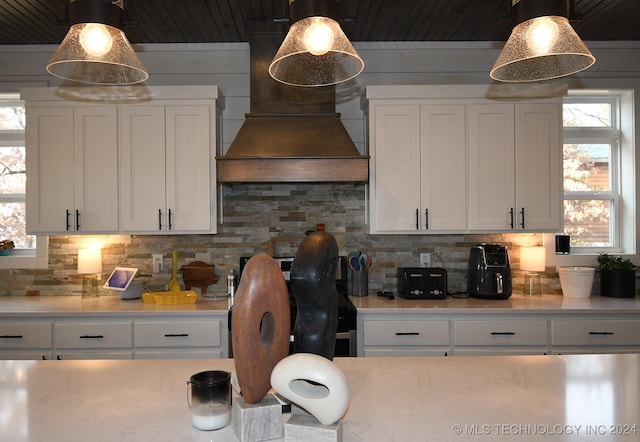 kitchen featuring pendant lighting, white cabinetry, plenty of natural light, and custom range hood