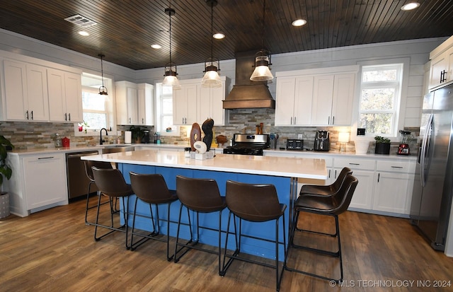 kitchen featuring white cabinets, decorative light fixtures, a kitchen island, and stainless steel appliances