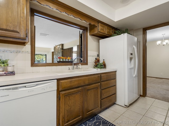 kitchen with sink, white appliances, light tile patterned floors, tasteful backsplash, and a chandelier