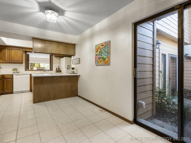 kitchen featuring white appliances, kitchen peninsula, decorative backsplash, sink, and light tile patterned flooring