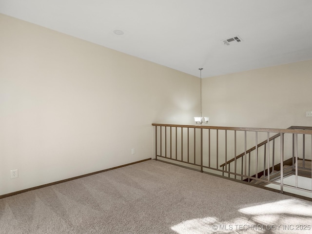 carpeted empty room featuring a notable chandelier