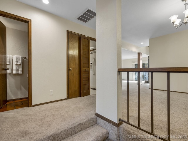 corridor with a chandelier and light colored carpet