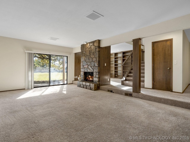 unfurnished living room with a stone fireplace and carpet floors