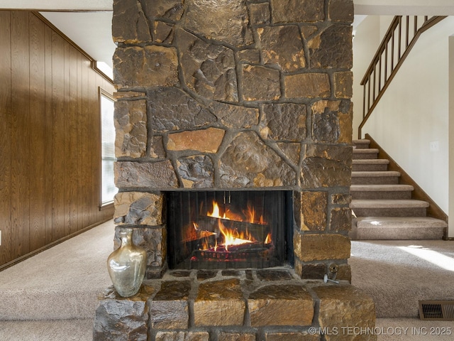 interior details with wooden walls, carpet flooring, and a stone fireplace