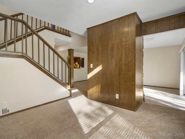 interior space featuring light colored carpet, wooden walls, and ornate columns