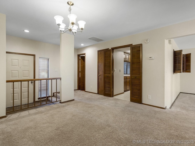 carpeted empty room with a notable chandelier