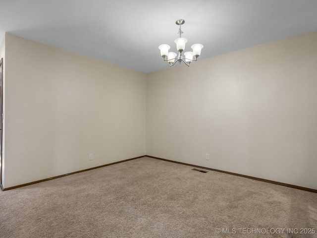 empty room featuring baseboards, a notable chandelier, and carpet