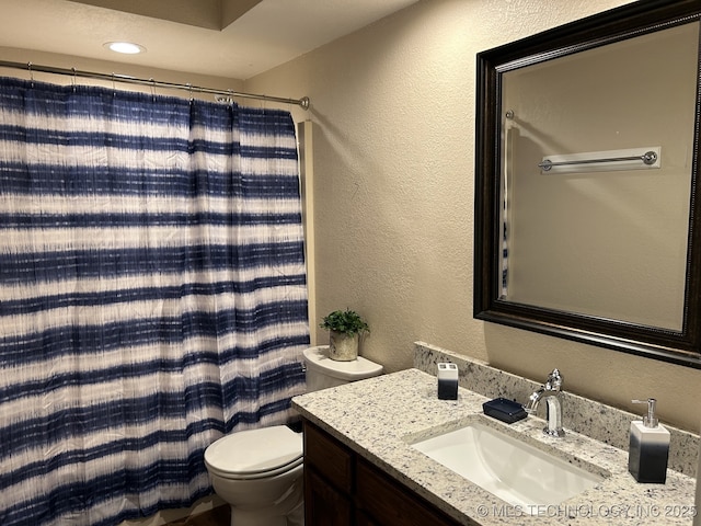 bathroom with vanity, a textured wall, curtained shower, and toilet