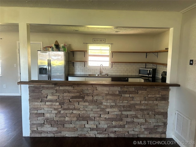 kitchen featuring decorative backsplash, appliances with stainless steel finishes, kitchen peninsula, sink, and dark hardwood / wood-style floors