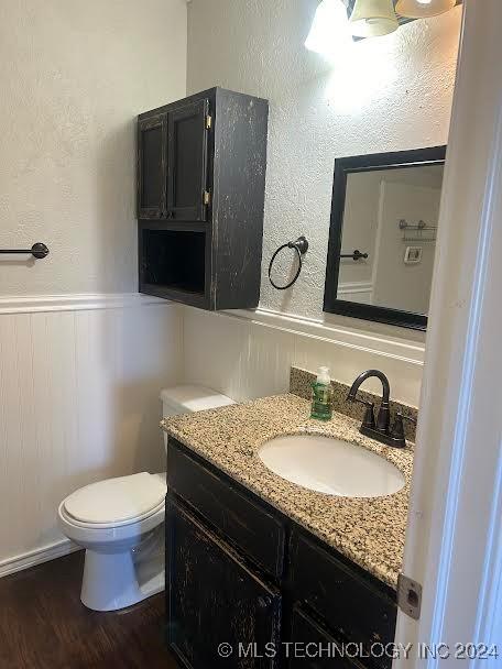 bathroom featuring wood-type flooring, vanity, and toilet