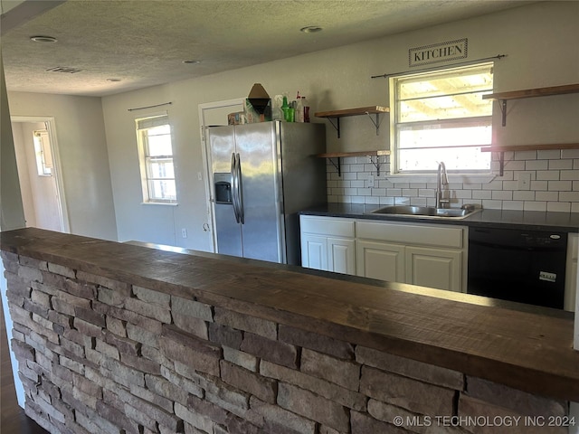 kitchen featuring dishwasher, backsplash, sink, stainless steel fridge, and white cabinetry