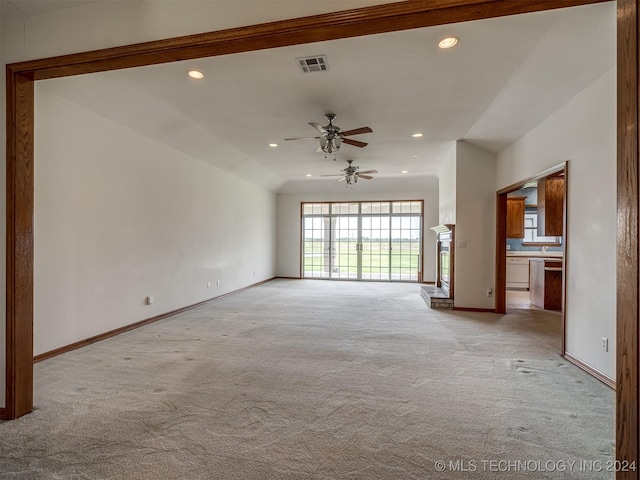 unfurnished living room with ceiling fan, lofted ceiling, and light carpet