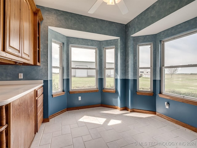 unfurnished dining area with ceiling fan and light tile patterned flooring