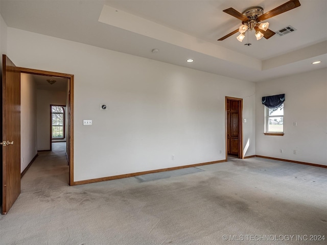 carpeted empty room featuring ceiling fan and a raised ceiling