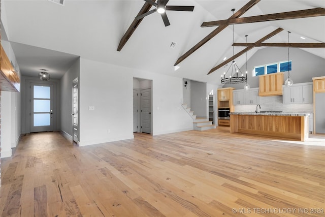 unfurnished living room with beamed ceiling, light wood-type flooring, high vaulted ceiling, and ceiling fan with notable chandelier