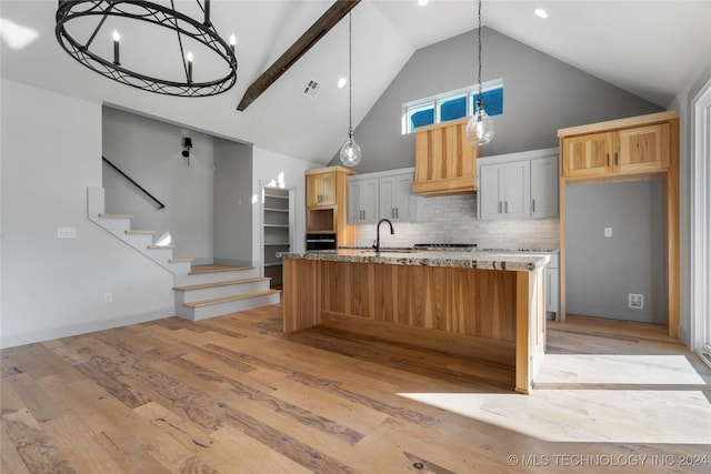 kitchen featuring high vaulted ceiling, white cabinets, light hardwood / wood-style flooring, decorative backsplash, and light stone counters