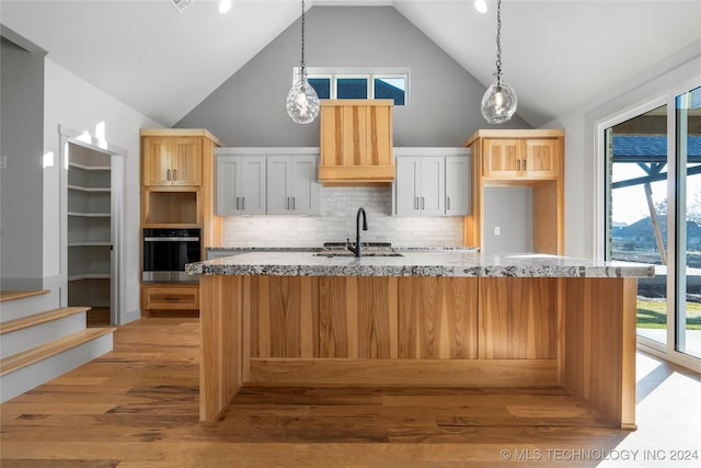 kitchen with stainless steel oven, light stone counters, high vaulted ceiling, white cabinets, and light wood-type flooring