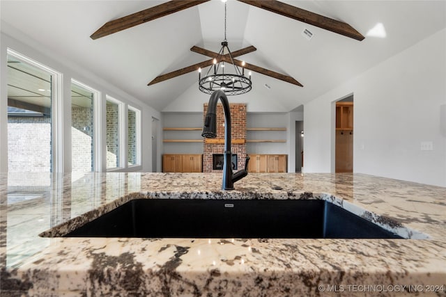 kitchen featuring a wood stove, lofted ceiling with beams, sink, light stone countertops, and a chandelier