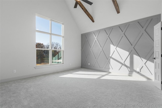 carpeted empty room featuring beamed ceiling, ceiling fan, and high vaulted ceiling