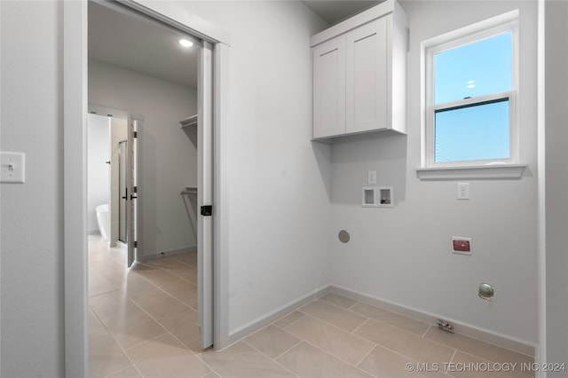 clothes washing area featuring cabinets, light tile patterned floors, and washer hookup