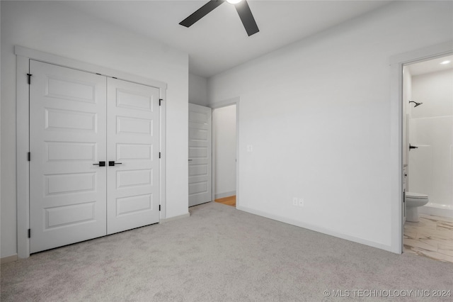 unfurnished bedroom featuring light carpet, a closet, ensuite bath, and ceiling fan