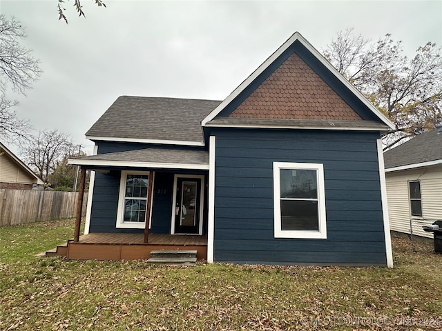 rear view of property with covered porch and a yard