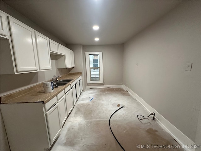 kitchen featuring white cabinets, wood counters, and sink