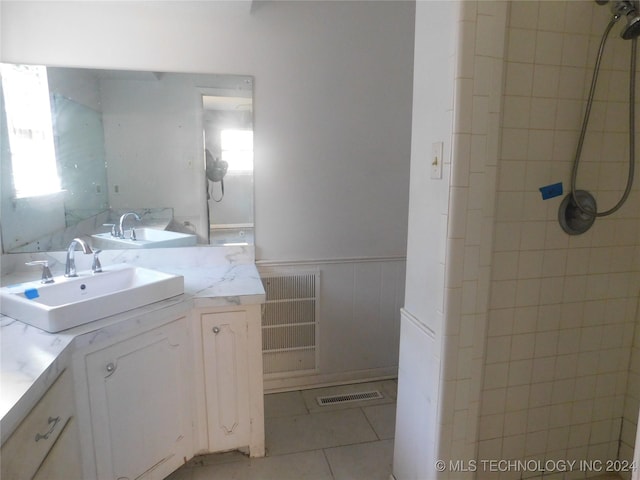 bathroom with a tile shower, vanity, and tile patterned floors