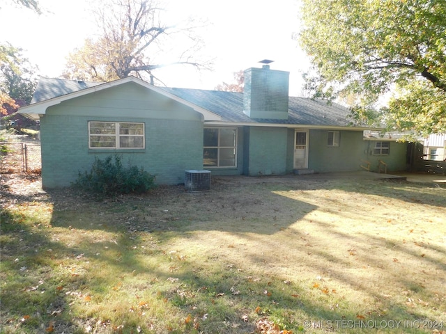 back of property with central AC and a yard