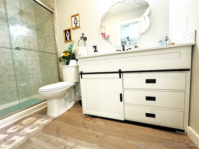 bathroom with hardwood / wood-style floors, vanity, toilet, and a shower with door