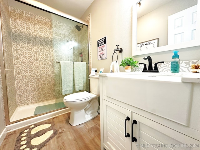 bathroom featuring vanity, toilet, wood-type flooring, and a shower with door