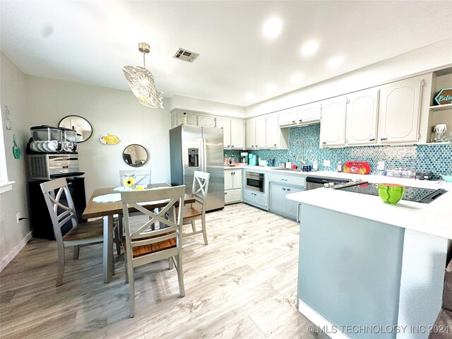 kitchen featuring decorative backsplash, stainless steel appliances, hanging light fixtures, and light hardwood / wood-style flooring