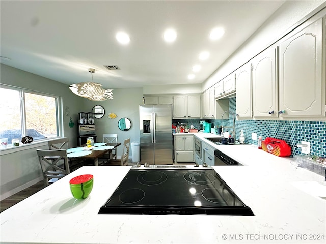 kitchen featuring an inviting chandelier, backsplash, wood-type flooring, pendant lighting, and appliances with stainless steel finishes