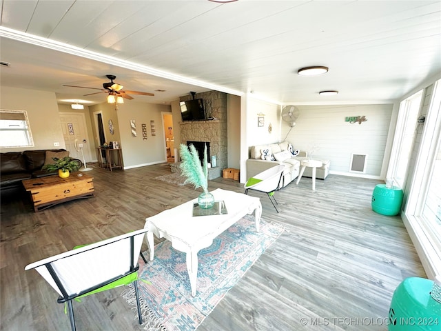 living room featuring hardwood / wood-style floors, a stone fireplace, and ceiling fan