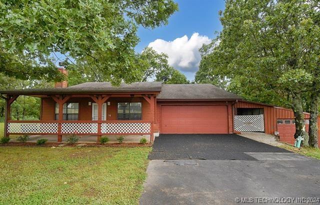 view of front of property featuring covered porch, a garage, and a front lawn