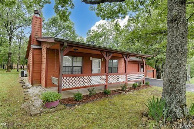 view of front of property with an outdoor structure, a porch, a front yard, and a garage