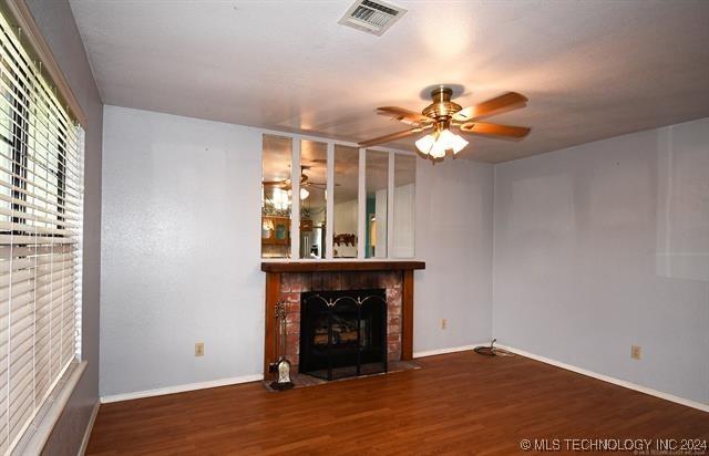 unfurnished living room featuring dark hardwood / wood-style flooring, a brick fireplace, and ceiling fan