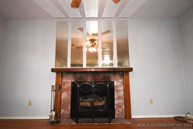 details featuring hardwood / wood-style flooring, ceiling fan, and a brick fireplace