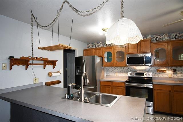 kitchen with backsplash, sink, ceiling fan, appliances with stainless steel finishes, and decorative light fixtures