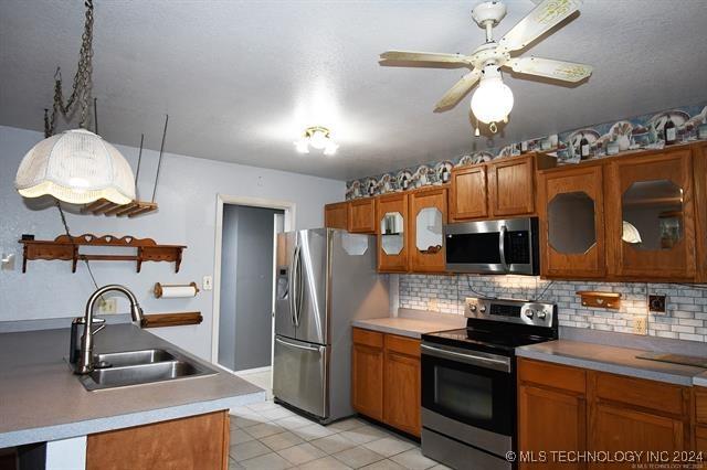 kitchen with backsplash, sink, ceiling fan, light tile patterned floors, and appliances with stainless steel finishes