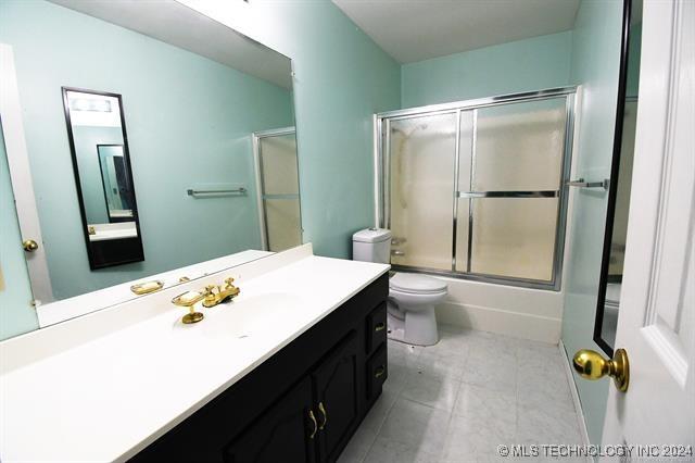 full bathroom with vanity, toilet, and enclosed tub / shower combo