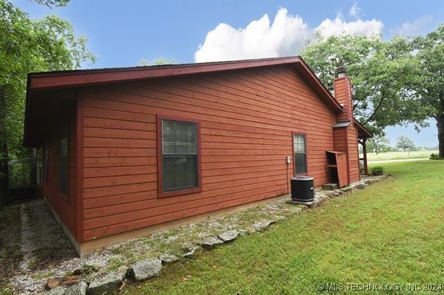 view of side of home featuring a lawn and central air condition unit