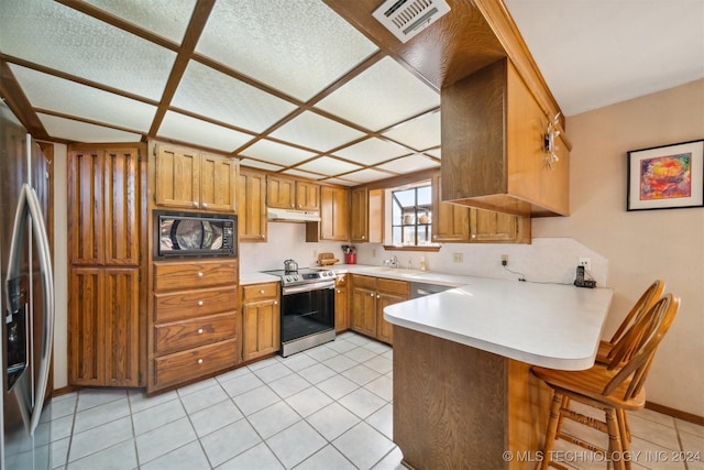 kitchen with light tile patterned flooring, sink, kitchen peninsula, and stainless steel appliances