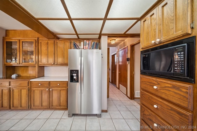 kitchen featuring a textured ceiling, stainless steel fridge, light tile patterned floors, and black microwave