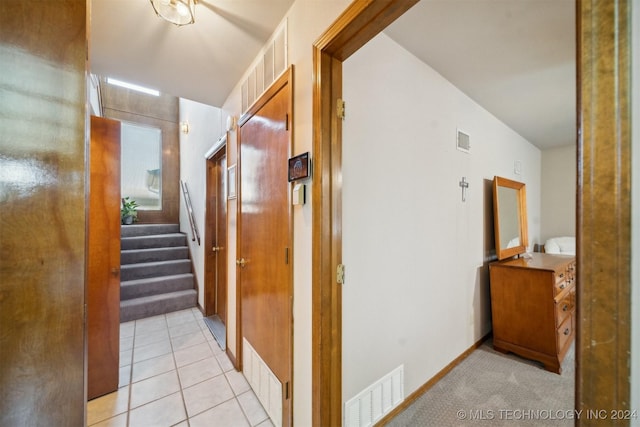 corridor featuring light tile patterned floors and lofted ceiling