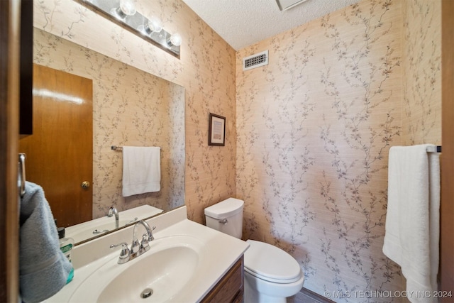 bathroom featuring vanity, a textured ceiling, and toilet