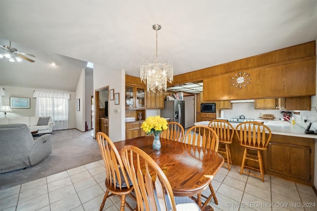 tiled dining area with ceiling fan with notable chandelier and vaulted ceiling