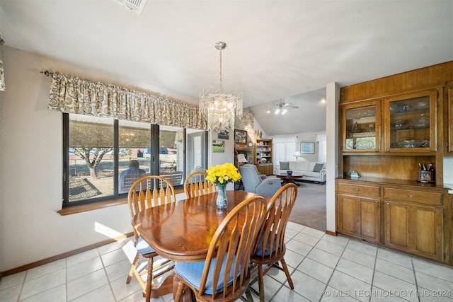 dining area with ceiling fan with notable chandelier, light tile patterned floors, and vaulted ceiling