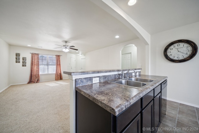 kitchen with ceiling fan, dishwasher, sink, a kitchen island with sink, and dark carpet